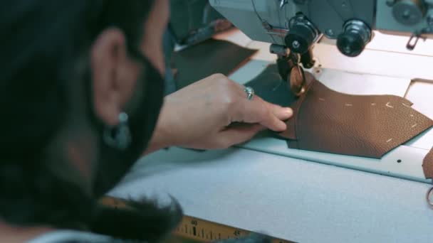Machine à coudre dans un atelier de cuir en action avec des mains travaillant sur un détail en cuir pour chaussures. Macro shot de mains de femmes avec machine à coudre à l'usine de chaussures — Video