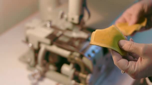 Machine à coudre dans un atelier de cuir en action avec des mains travaillant sur un détail en cuir pour chaussures. Macro shot de mains de femmes avec machine à coudre à l'usine de chaussures — Video