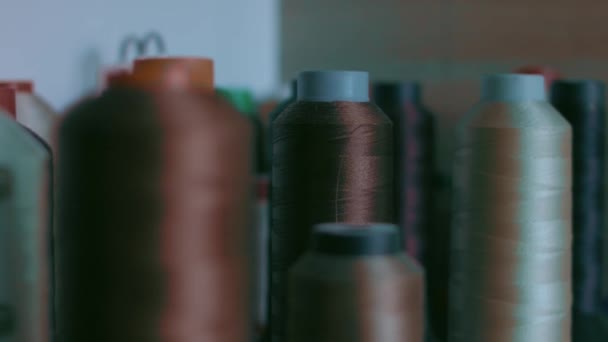 Spoelen draad voor het naaien van schoenen in donkere kleuren staan op een plank — Stockvideo