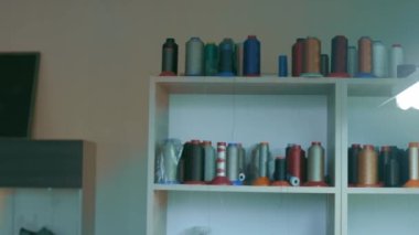 Koyu renkli ayakkabı dikmek için iplik makaraları bir rafta duruyor