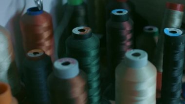 Koyu renkli ayakkabı dikmek için iplik makaraları bir rafta duruyor