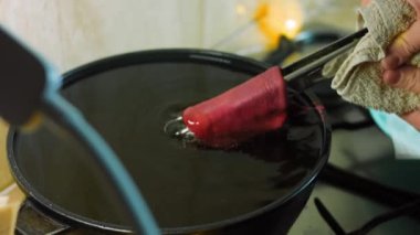 Şef yağlı bir kasede kırmızı tortilla pişirir..