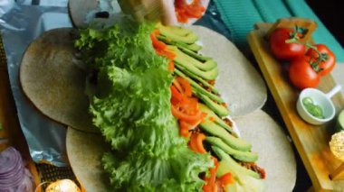 Şef domates slaytlarını burrito 'nun üzerine yerleştirir..