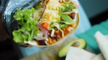 Şef büyük bir Buritto ile avokado ve sucuklu etle dans ediyor. Romantik bir ortamda çekim yapmak..