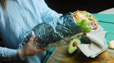 Şef büyük bir Buritto ile avokado ve sucuklu etle dans ediyor. Romantik bir ortamda çekim yapmak..