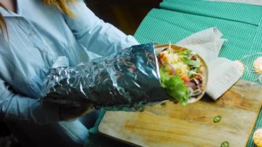 Şef büyük bir Buritto ile avokado ve sucuklu etle dans ediyor. Romantik bir ortamda çekim yapmak..