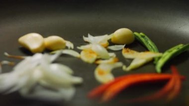 Şef sebze kızartıyor. Kahverengi kırmızı ve yeşil soğan ve biber.