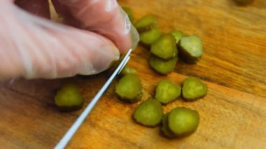 Şef küçük salatalıkları dilimlere ayırır..