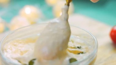 Aşçı altın kaşıkla karıştırır mayonez sosu küçük salatalık turşusu.