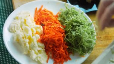 Şef masaya mozzarella peyniri, kırmızı ve yeşil pesto ile bir tabak koyar..