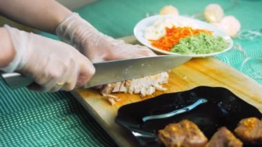 Şef taze pişmiş eti parçalara ayırır..