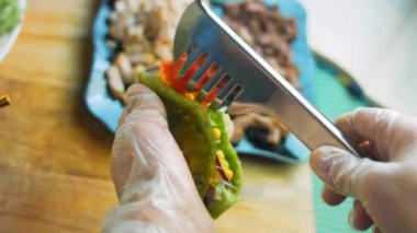 Şef taco hazırlıyor. Dilimlenmiş domates ekle.