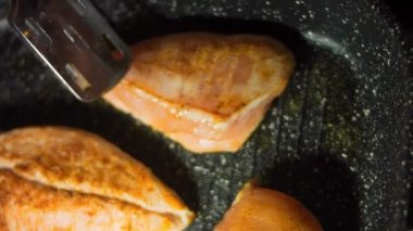 Şef ızgarada pişmiş tavuğu yemek maşasıyla pişiriyor..