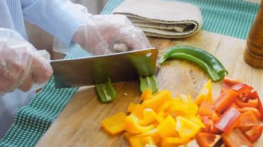Şef yeşil ve acı biberleri profesyonel bir bıçakla keser..