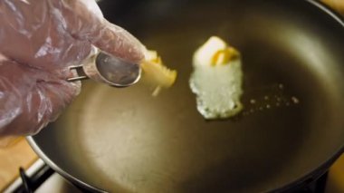 Aşçı tavaya bir yemek kaşığı tereyağı koyar..