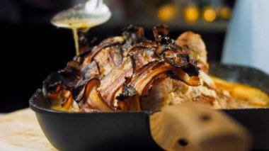 Domuz pastırması sarılı domuz filetosu. Elma suyu tarifinde kızartılmış. Aşçı et parçalarının üzerine sos döker..