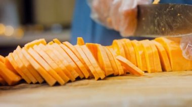 Şef tatlı patatesleri dilimlere ayırır. Arka planda romantik atmosfer.