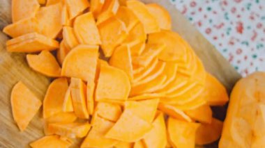 Şef tatlı patatesleri dilimlere ayırır. Arka planda romantik atmosfer.