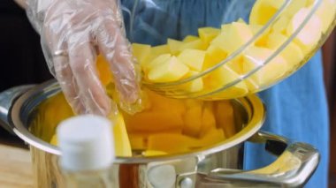 Aşçı patatesleri kaynatmak için tencereye koyar..