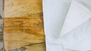 Şef brie peyniri keser. Arka planda gıda kağıdı süslemeleri.