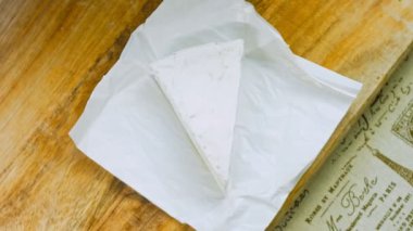 Şef brie peyniri keser. Arka planda gıda kağıdı süslemeleri.
