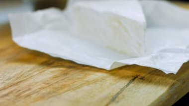 Şef brie peyniri keser. Arka planda gıda kağıdı süslemeleri.