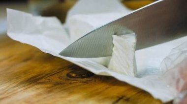 Şef brie peyniri keser. Arka planda gıda kağıdı süslemeleri.