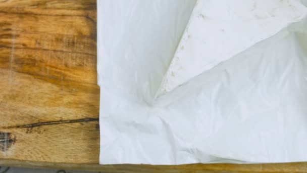 シェフはブリーチーズをカットします 背景に食品紙の装飾 — ストック動画