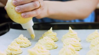 Şef bir yemek poşeti kullanarak patates kurabiyesi yapar. Patates kurabiyeleri kanonik tarif Brie, parmesan peyniri ve ağır krema