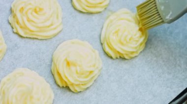 Şef patates kurabiyelerini fırçayla yağlıyor. Patates kurabiyeleri kanonik tarif Brie, parmesan peyniri ve ağır krema