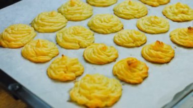 Patates kurabiyeleri kanonik peynir, parmesan peyniri ve ağır krema. Parşömen kağıdıyla kaplı bir tepside patates kurabiyesi..