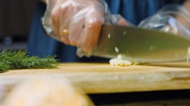 Aşçı bir diş sarımsağı bıçakla keser..