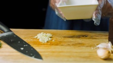 Aşçı bıçakla bir diş sarımsak kesti. Kare bir kap getir..