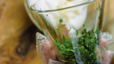 Şef çiftlik sosu için malzemelere doğranmış maydanoz koyar. Macro film çekiyor, altın kaşık kullan..