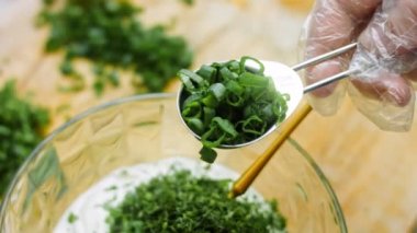 Şef, çiftlik sosu malzemelerine bir çorba kaşığı taze soğan dilimi koyar..