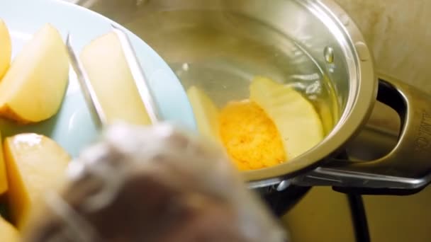 料理人はジャガイモを食べ物のトングで沸騰水に入れます — ストック動画