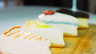 Arka arkaya dizilmiş dört çeşit cheesecake. Kaypak ve makro atış. Bir retro stil pişirme tahtası kullanılır.