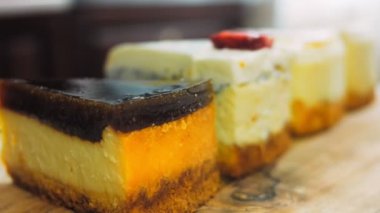Arka arkaya dizilmiş dört çeşit cheesecake. Kaypak ve makro atış. Bir retro stil pişirme tahtası kullanılır.
