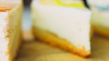 Arka arkaya dizilmiş dört çeşit cheesecake. Kaypak ve makro atış. Bir retro stil pişirme tahtası kullanılır.