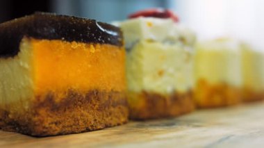 Arka arkaya dizilmiş dört çeşit cheesecake. Kaypak ve makro atış. Bir retro stil pişirme tahtası kullanılır.