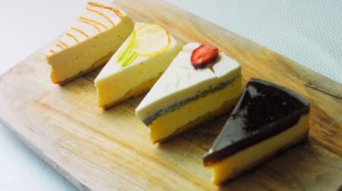 Arka arkaya dizilmiş dört çeşit cheesecake. Kaypak ve makro atış. Bir retro stil pişirme tahtası kullanılır.