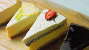 Arka arkaya dizilmiş dört çeşit cheesecake. Kaypak ve makro atış. Bir retro stil pişirme tahtası kullanılır.