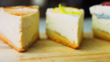 Arka arkaya dizilmiş dört çeşit cheesecake. Kaypak ve makro atış. Bir retro stil pişirme tahtası kullanılır.