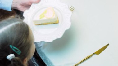 Şef tabağı masaya koyar. Retro tabakta limonlu cheesecake. Altın çatal ve bıçak kullan..