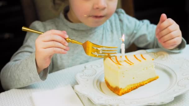 レトロなプレートにキャラメルチーズケーキ 金のフォークとナイフを使用してください 女の子はフォークでケーキを食べている 背景の女の子は楽しんでいる 誕生日を祝います — ストック動画