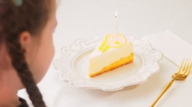 Retro tabakta limonlu cheesecake. Altın çatal ve bıçak kullan. Pastanın üzerindeki yanan mumu üfle. Doğum gününü kutluyoruz..