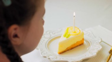 Retro tabakta limonlu cheesecake. Altın çatal ve bıçak kullan. Pastanın üzerindeki yanan mumu üfle. Doğum gününü kutluyoruz..