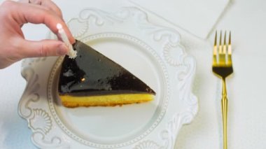 Retro tabakta cheesecake tiramisu. Altın çatal ve bıçak kullan. Kadın bir kibritle şekilli mumu yakar. Doğum gününü kutluyoruz..