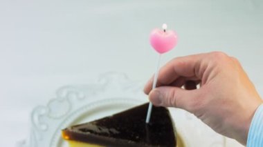 Retro tabakta cheesecake tiramisu. Altın çatal ve bıçak kullan. Kadın kalp şeklindeki mumu kibritle yakıyor. Doğum gününü kutluyoruz..