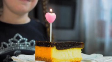 Retro tabakta cheesecake tiramisu. Altın çatal ve bıçak kullan. Kız bir dilek diliyor ve pastadaki mumu üflüyor. Doğum gününü kutluyoruz..